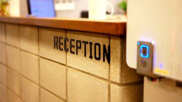 A reception area with a tiled wall and a digital device on the right.