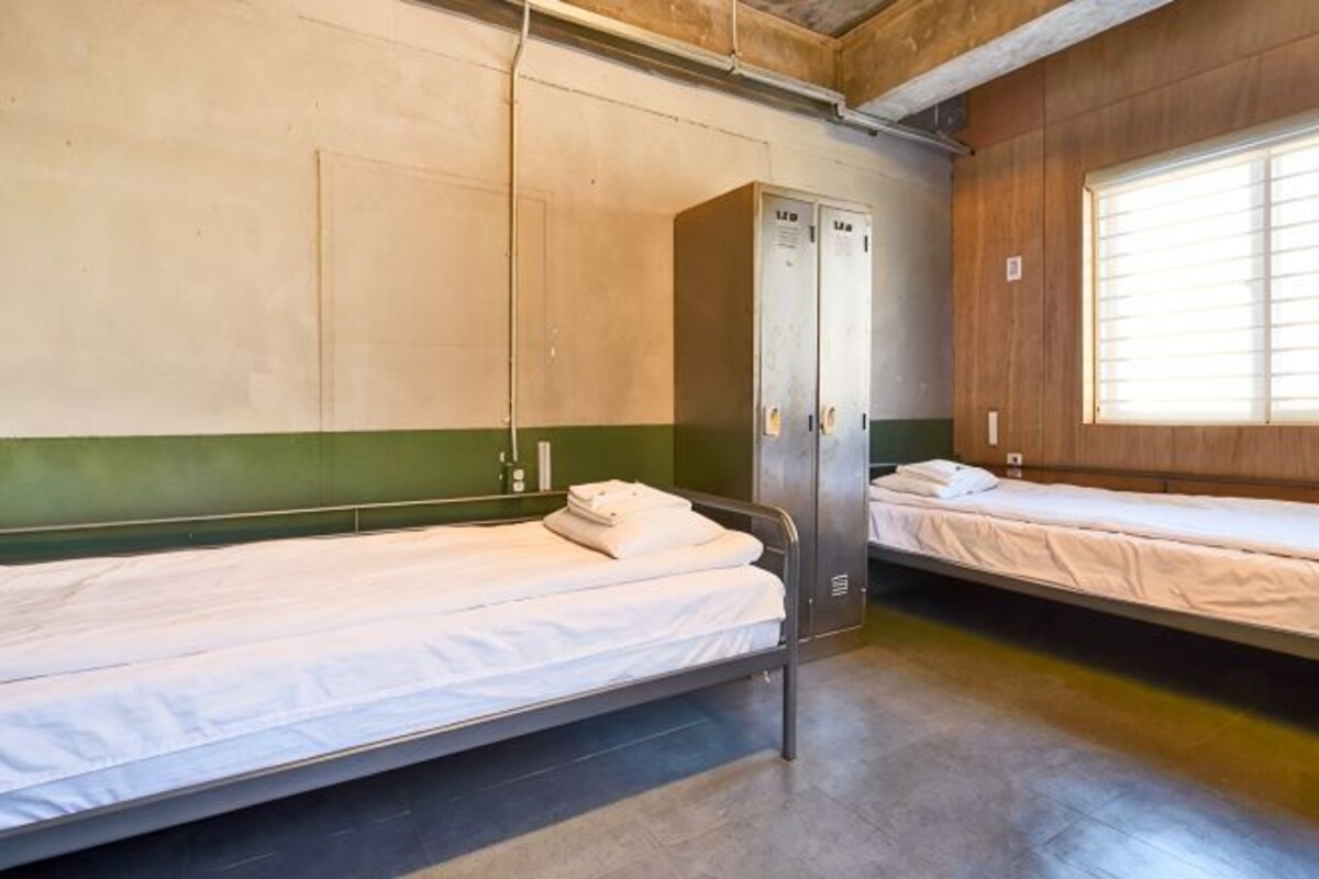 Un dormitorio con literas, un armario y una ventana con persianas.