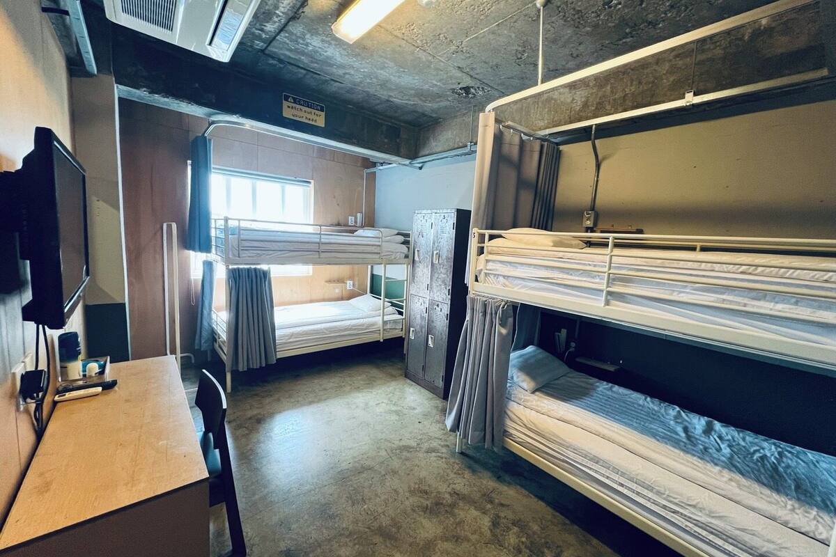 Une chambre avec des lits superposés, un bureau, une télévision et un panneau d’avertissement.