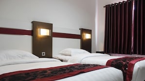 A hotel room with two beds, each with white linens and a red and black patterned throw. There are wall-mounted lights on either side of the bed heads. - Idea's Hotel (Bandung)