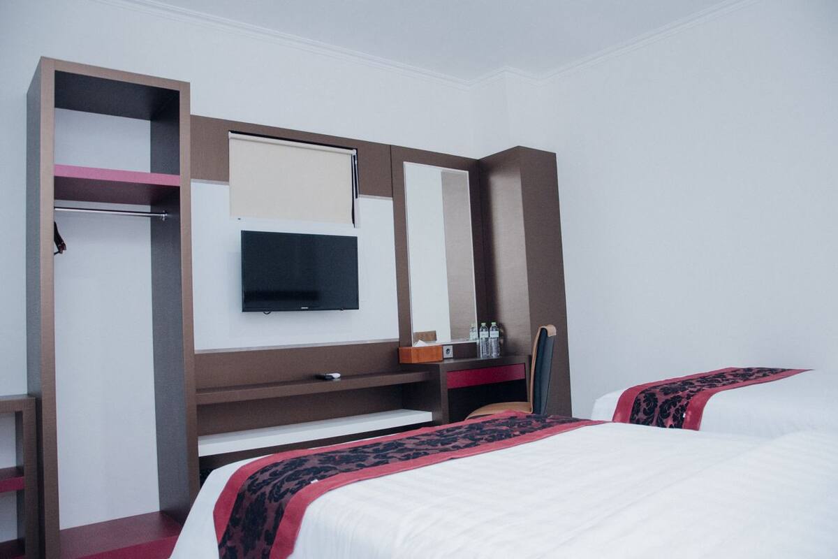 A hotel room with a bed, a TV, a desk, and a wardrobe.