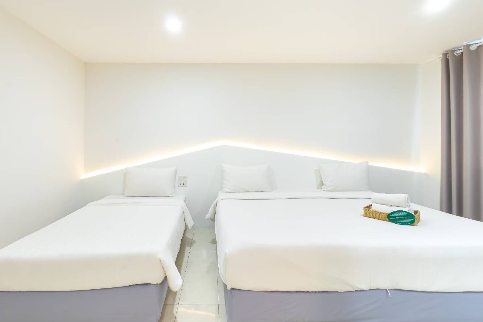 Une chambre d’hôtel avec deux lits simples, une table de chevet avec une boîte de mouchoirs et une décoration aux couleurs neutres.