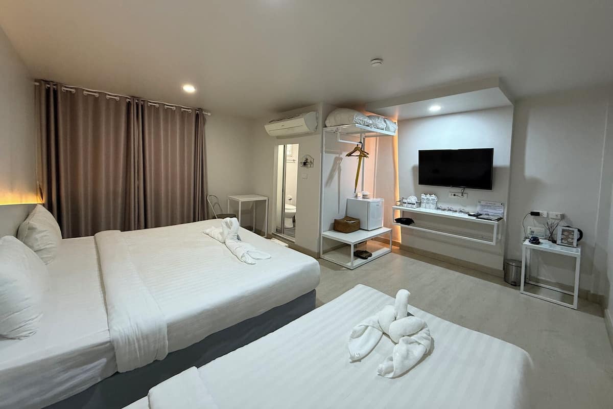 A hotel room with two beds, a TV, a desk, and a mirror.