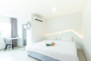 A modern hotel room with a large bed, a desk, and an air conditioning unit. - Bed by Boat Hotel & Apartment (Nonthaburi)