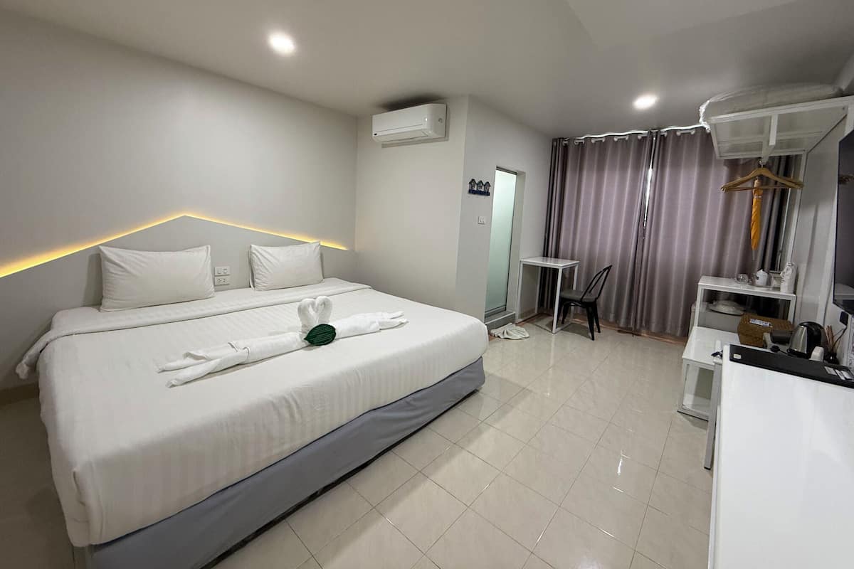 A modern hotel room with a neatly made bed, a desk, and a wardrobe.