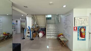 Um saguão de hotel com escada, extintor de incêndio e mapa na parede.
