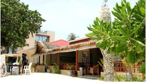A building with a thatched roof, surrounded by potted plants and a palm tree. - WhiteShell Island Hotel & Spa (Maafushi)