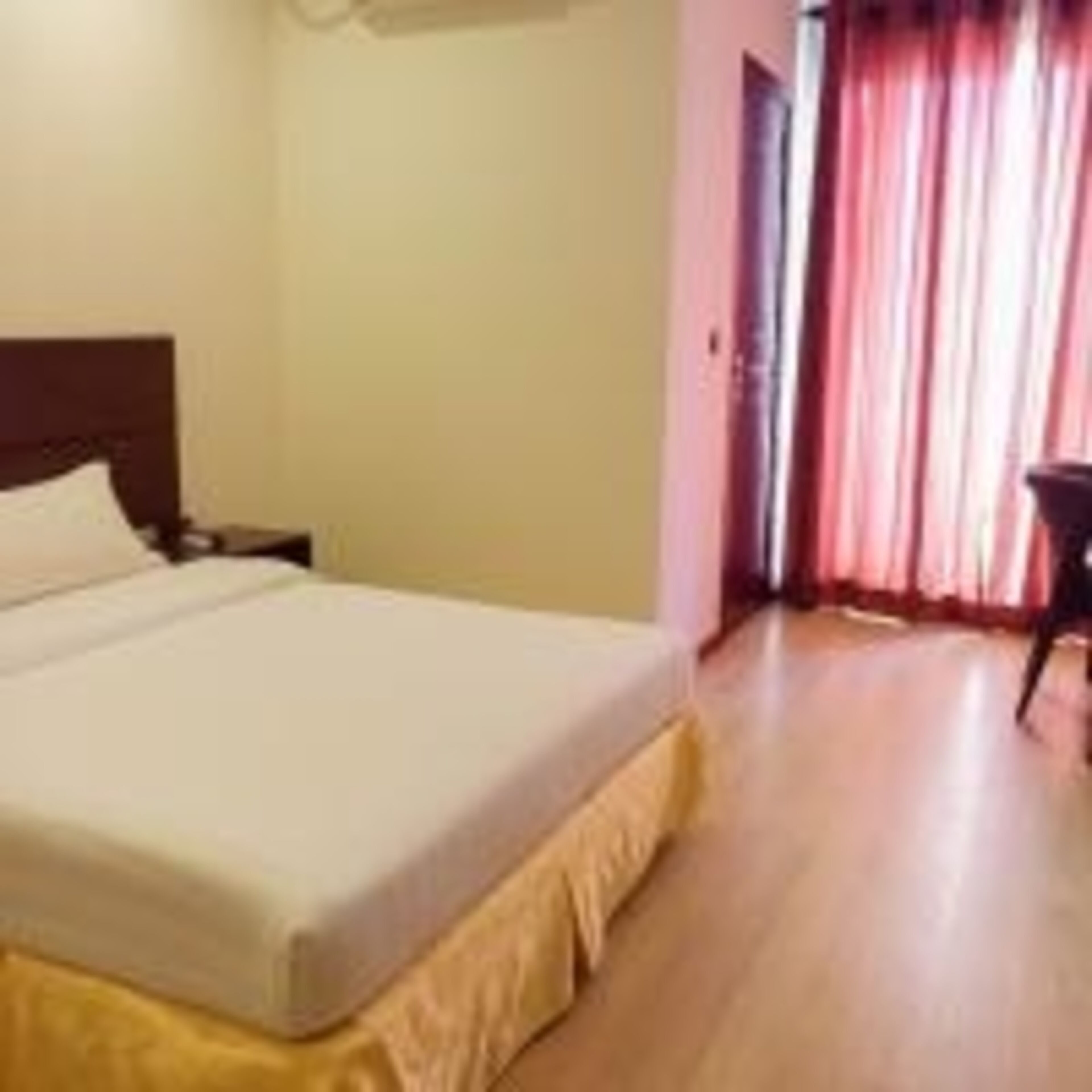 A hotel room with a bed, a nightstand, and a chair.