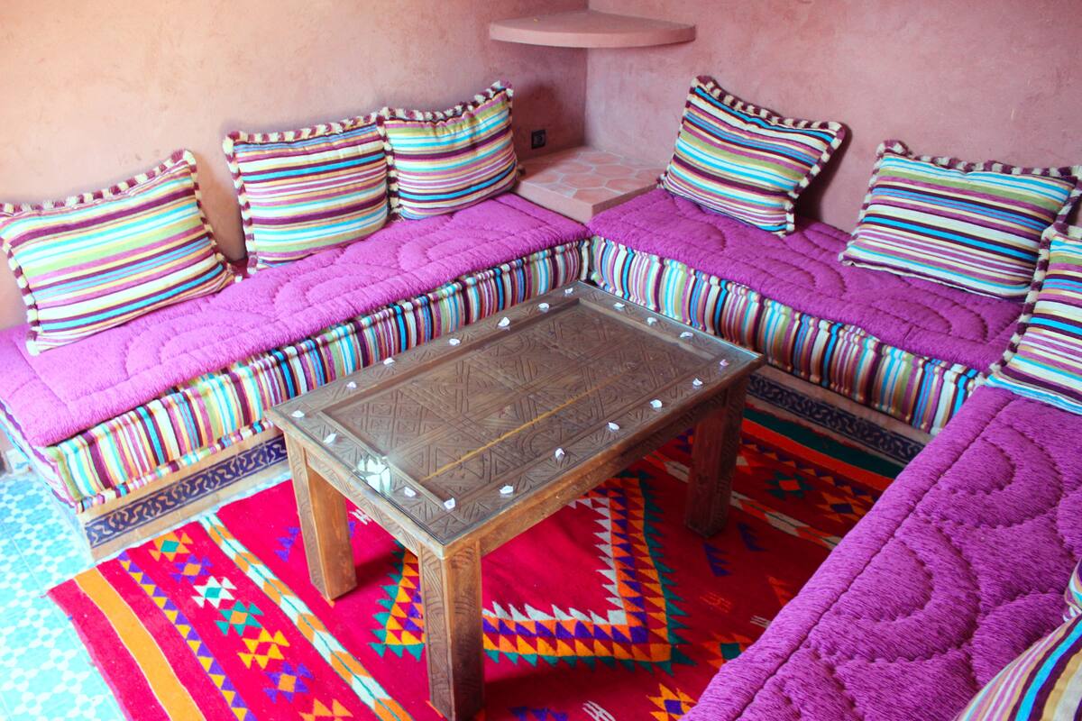 A cozy seating area with a wooden coffee table, colorful cushions, and a vibrant rug.