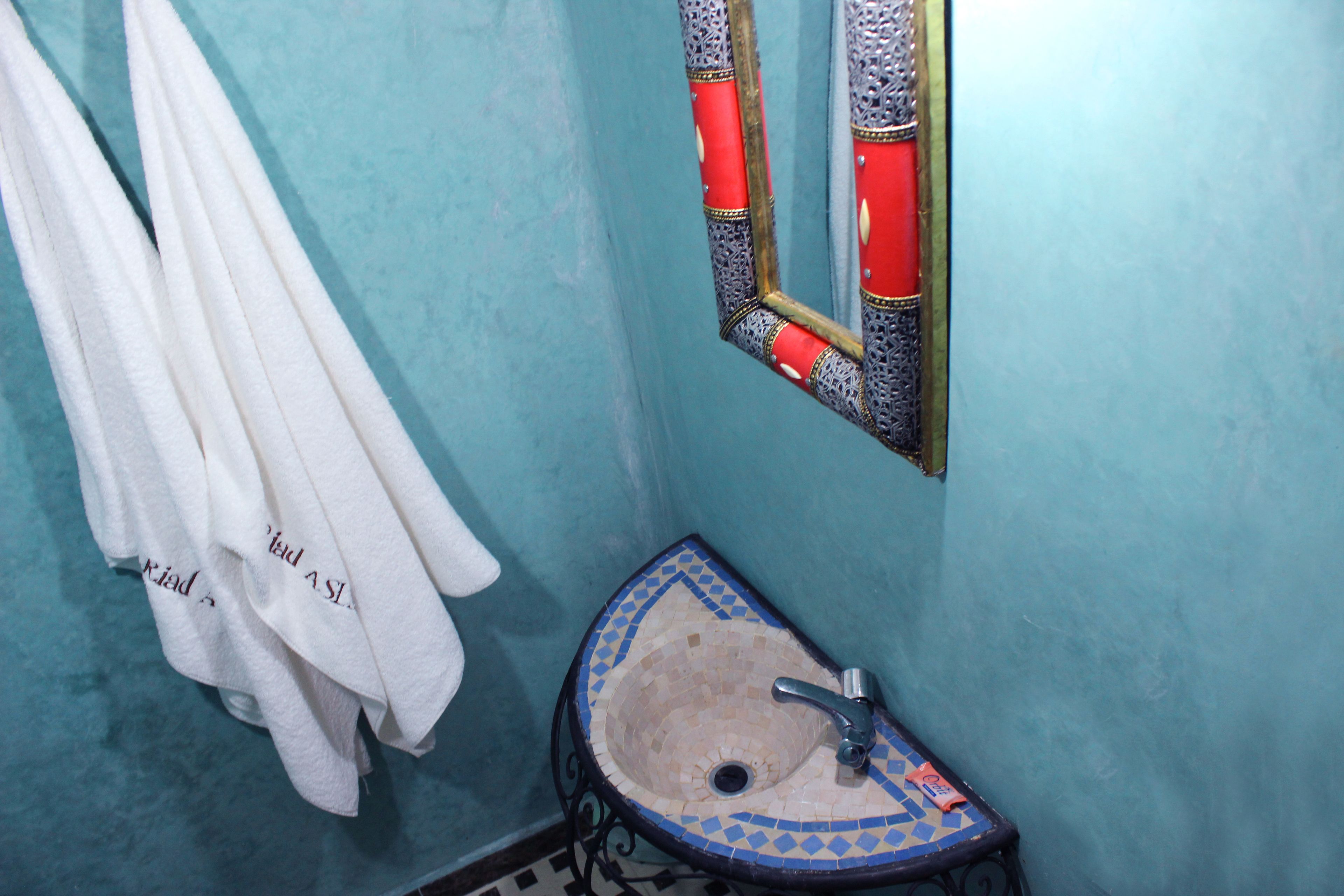 Une salle de bain avec un lavabo, un miroir et des serviettes suspendues.