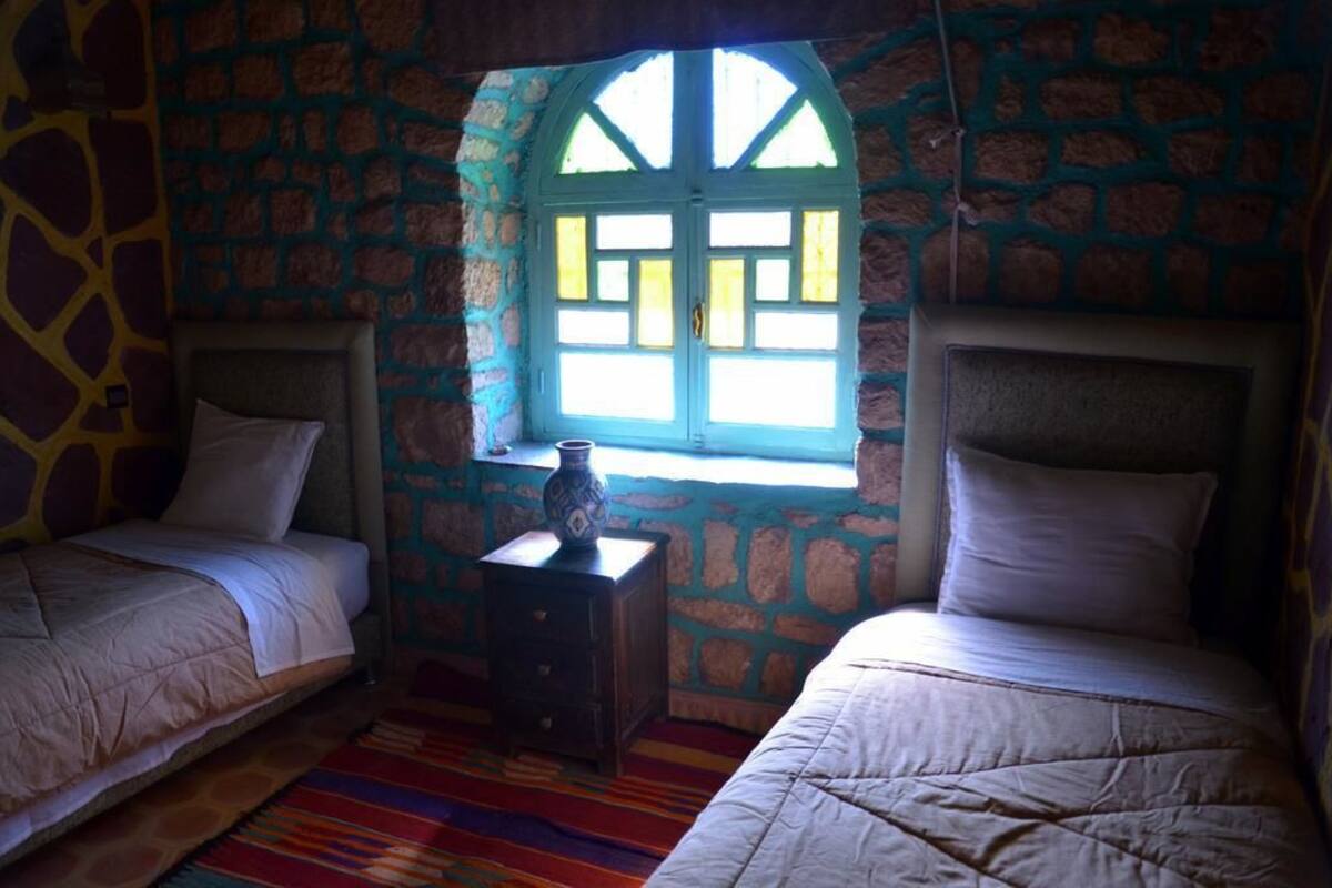 A room with two beds, a small table, and a window with a view.