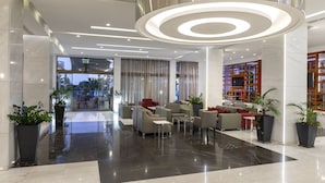 Um lobby moderno com área de estar, uma luminária circular grande e vista para o exterior.
