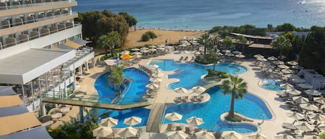 Relax by the infinity pool overlooking the ocean, surrounded by sun loungers and umbrellas.