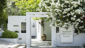 Un edificio blanco con un letrero que dice "Skiathos Holidays Resort" y un gran jarrón de flores.