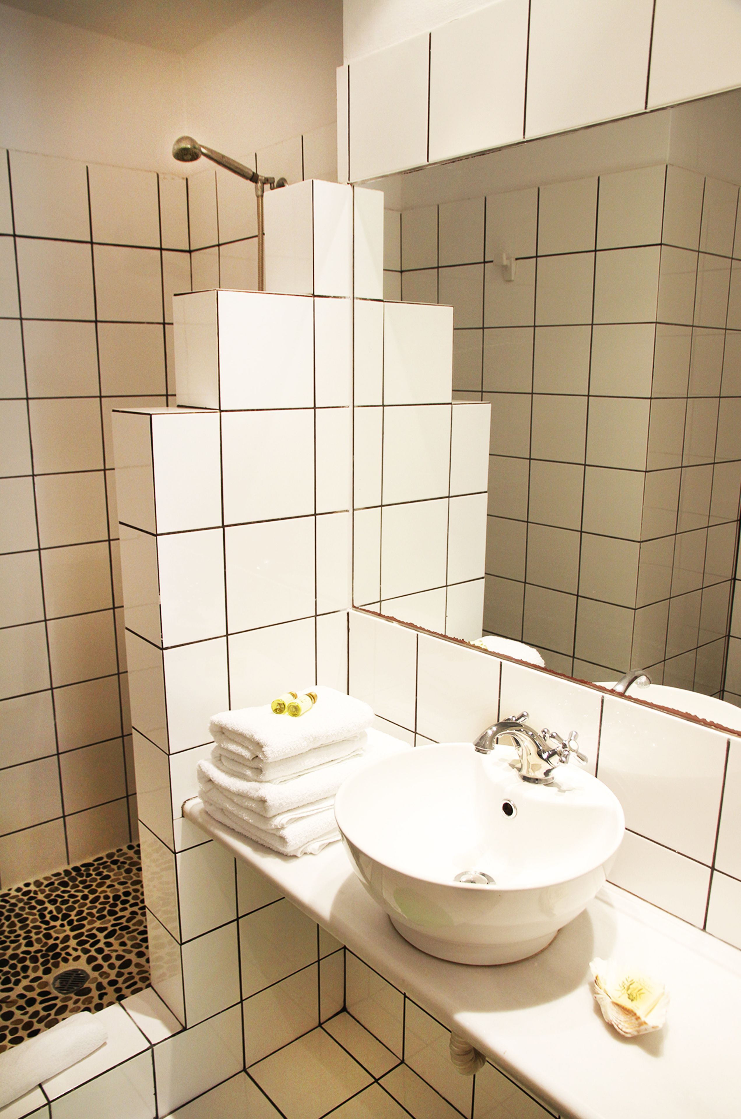 A bathroom with a white sink, a mirror, and a shower area.