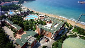 Vista aérea de un resort con varias edificaciones, una piscina grande y una playa.
