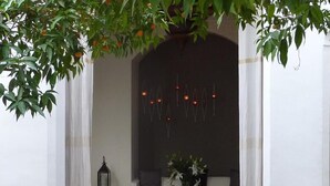Un rincón acogedor con alfombra roja, cojines blancos y una mesa con flores.