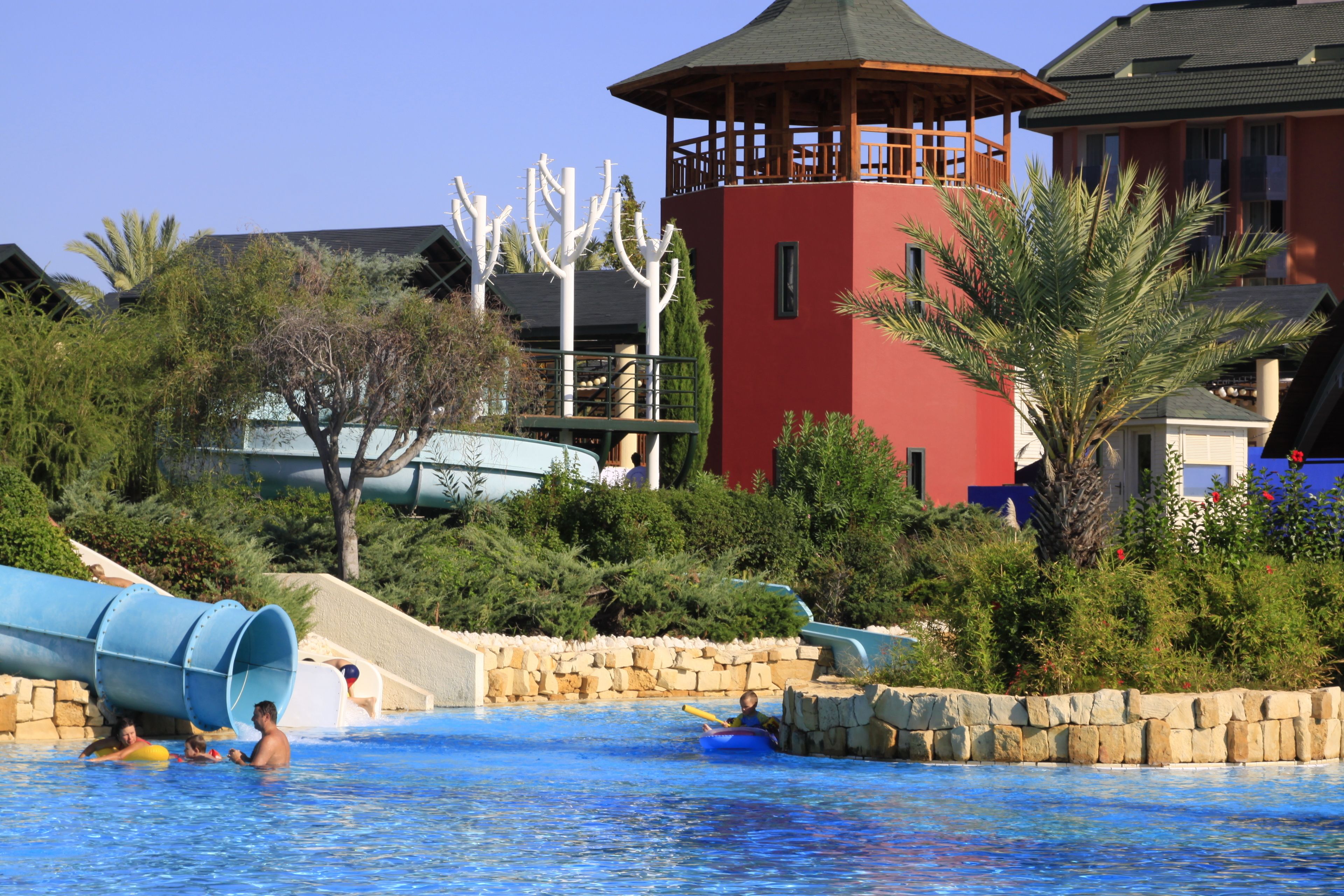Un parque acuático con una piscina grande, toboganes y una estructura tipo torre.