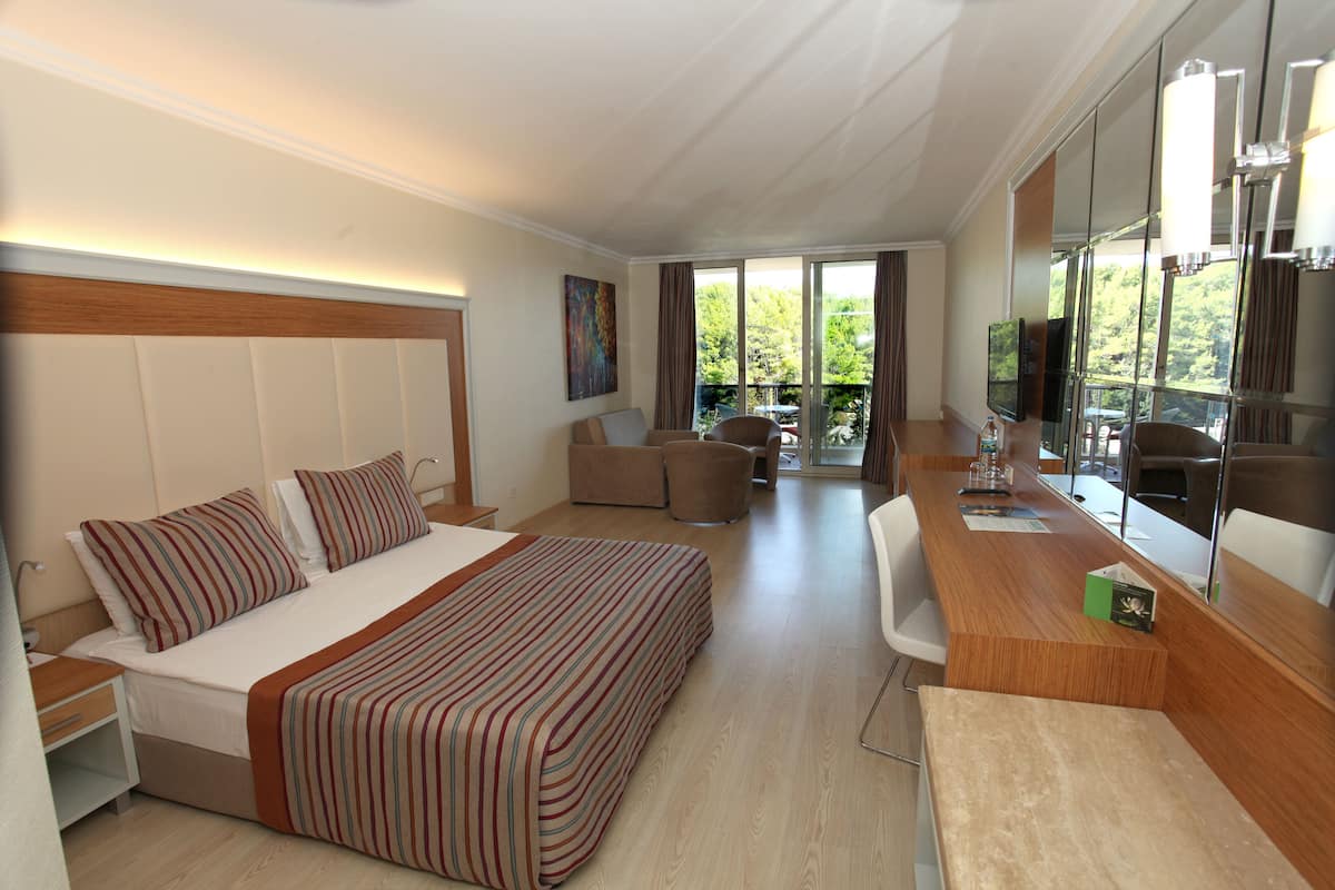 A modern hotel room with a large bed, a desk, and a seating area.
