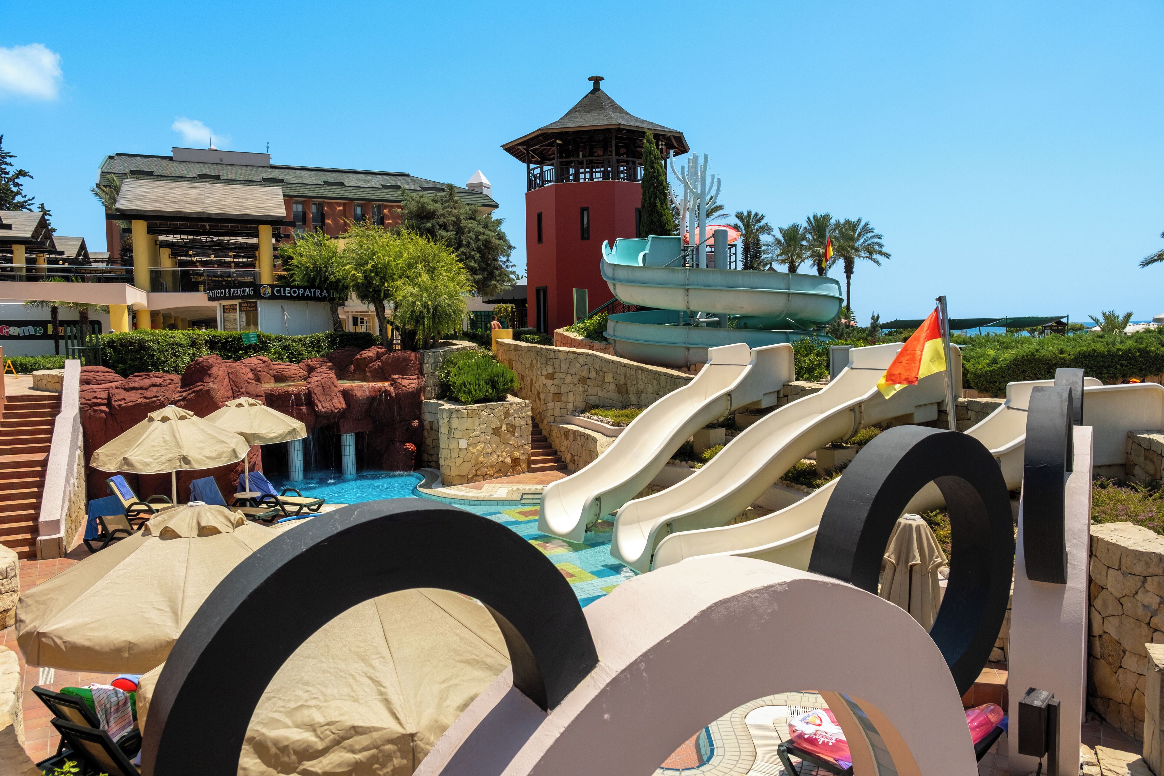 A water park with slides, a pool, and a building with a tower.