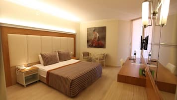 A hotel room with a large bed, bedside table, nightstand, and a mirror with lights.