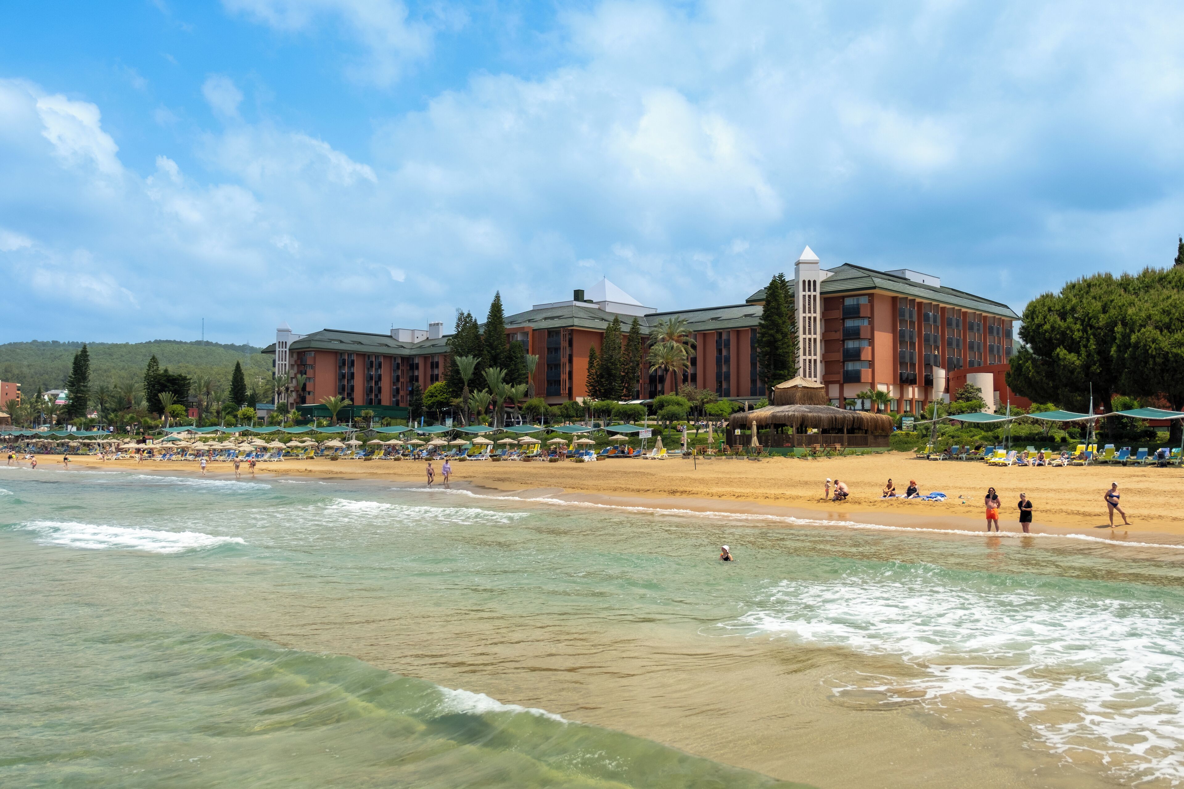 A beachfront hotel with multiple buildings, a sandy beach, and ocean waves.