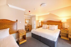 Una camera d'albergo con un letto grande, una testiera in legno, comodini, una cassettiera e uno specchio.