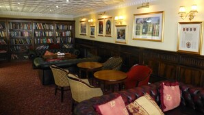 Une bibliothèque avec des étagères, des canapés en cuir et des tables.