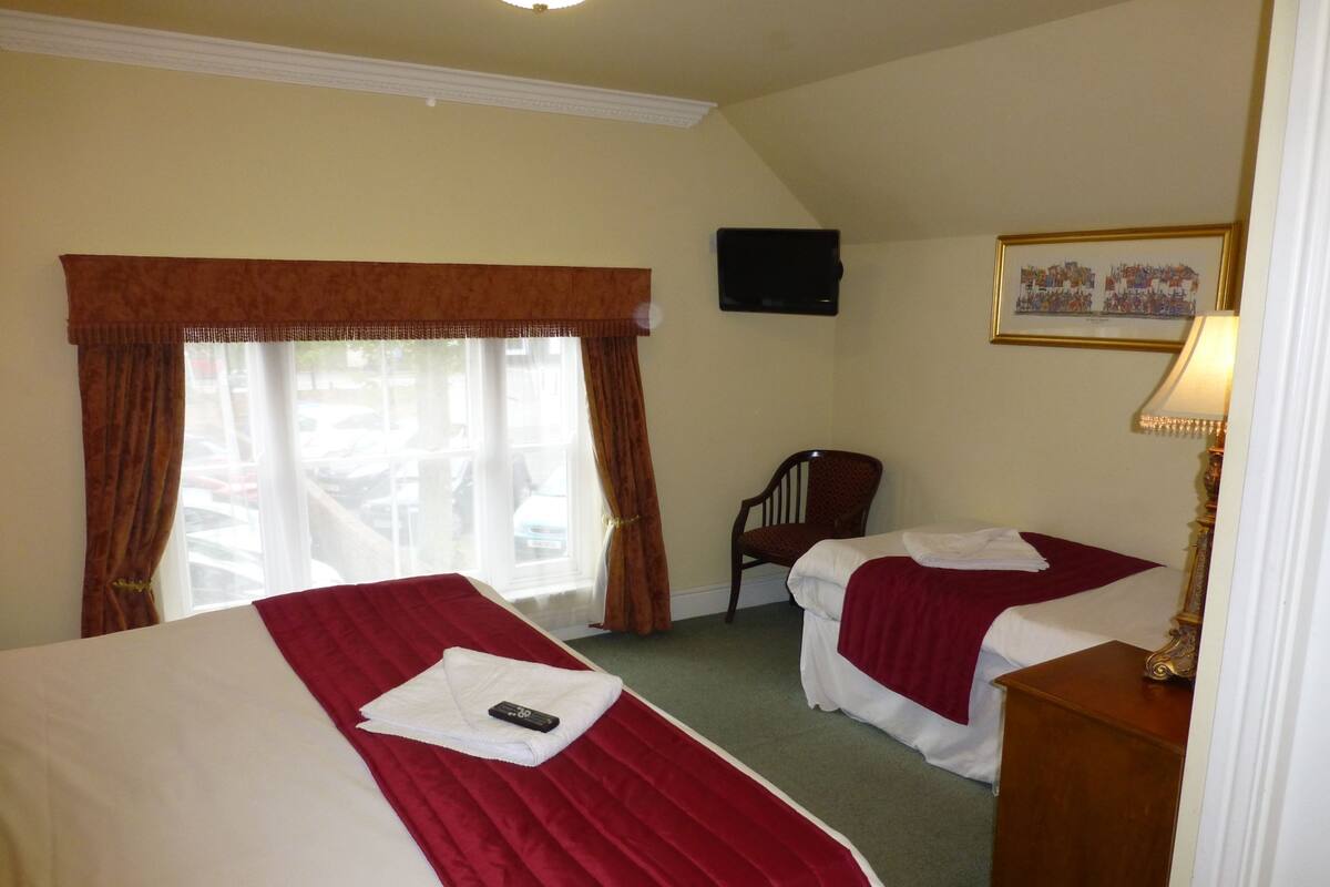 Une chambre d’hôtel avec deux lits, une chaise, un téléviseur et un tableau au mur.