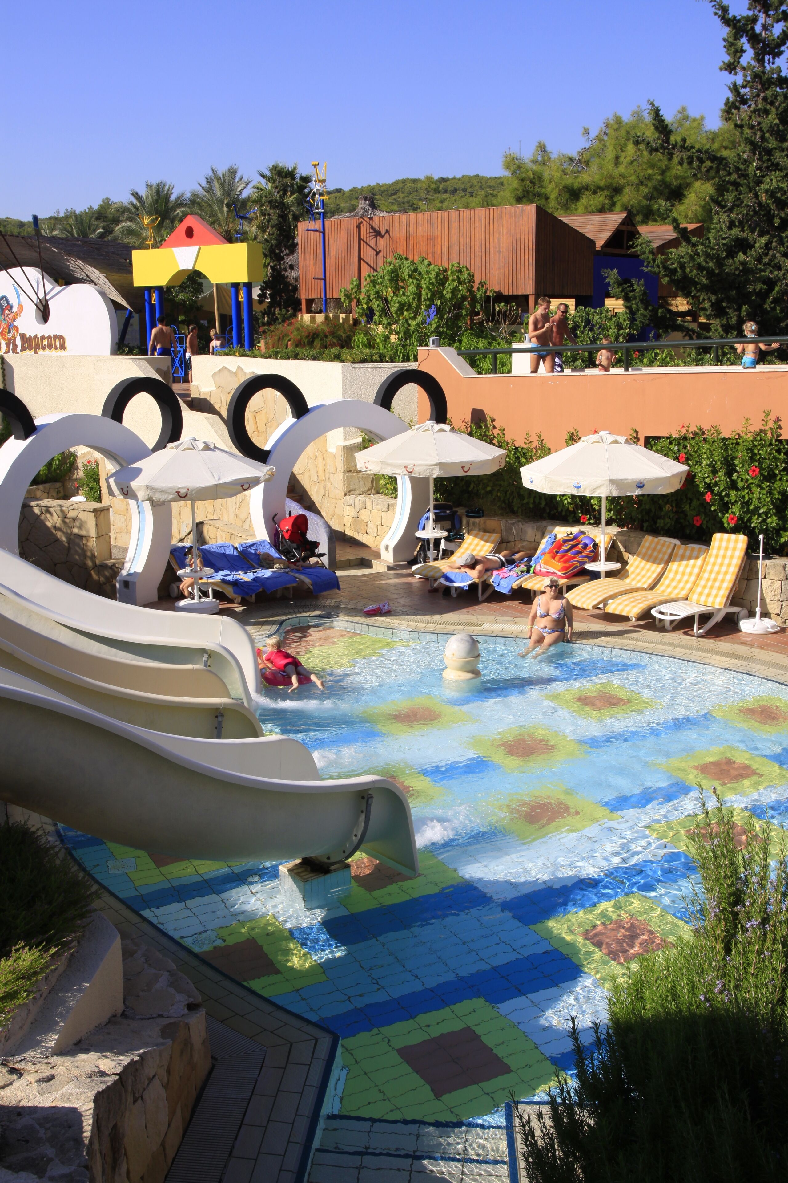 Parque acuático con toboganes, piscina y zonas de descanso con sombrillas.