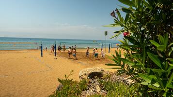 Ein Beachvolleyballfeld mit Spielern, einem Netz und einem Sandstrand.