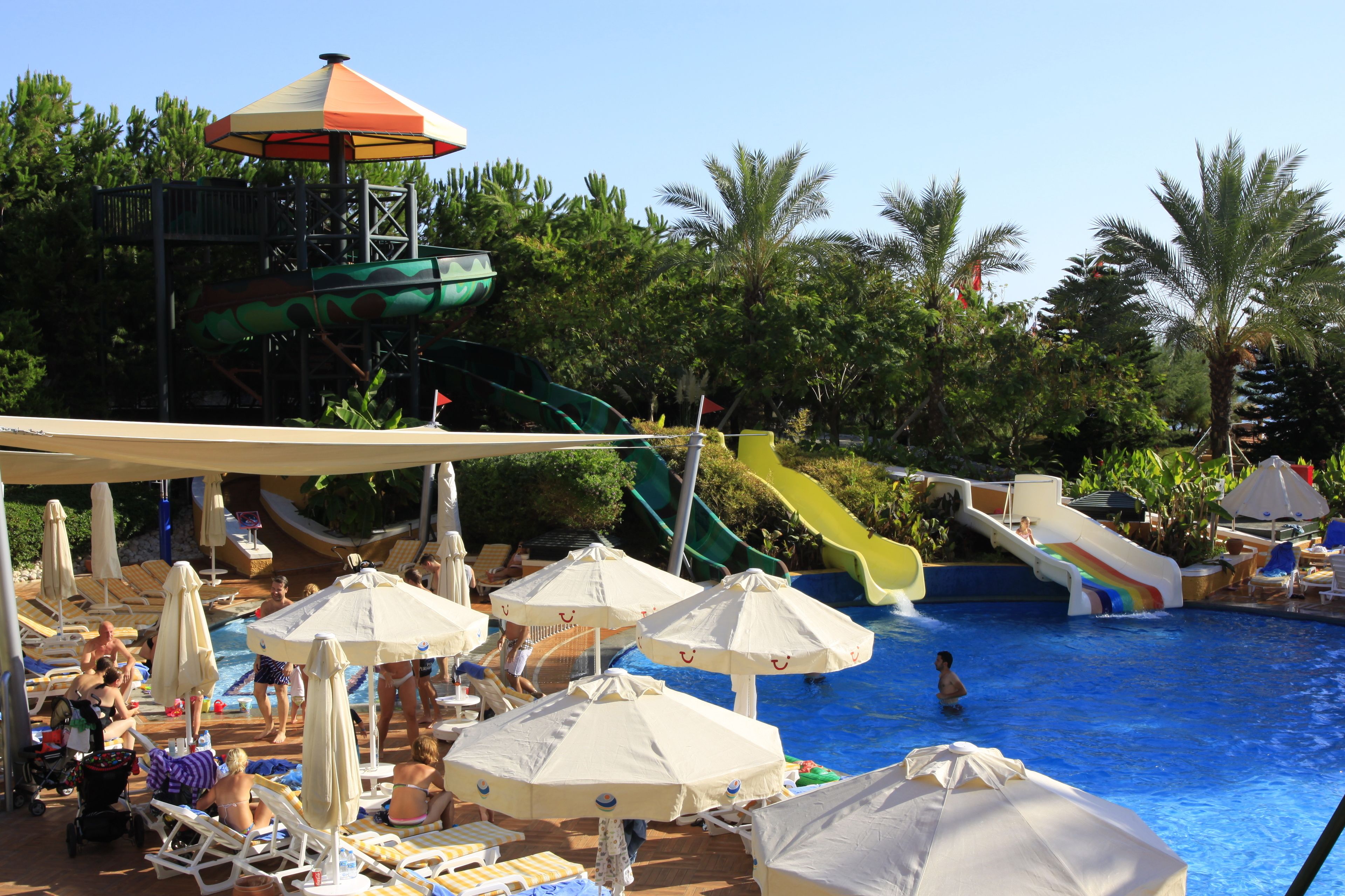 A pool area with multiple slides, umbrellas, and lounge chairs.