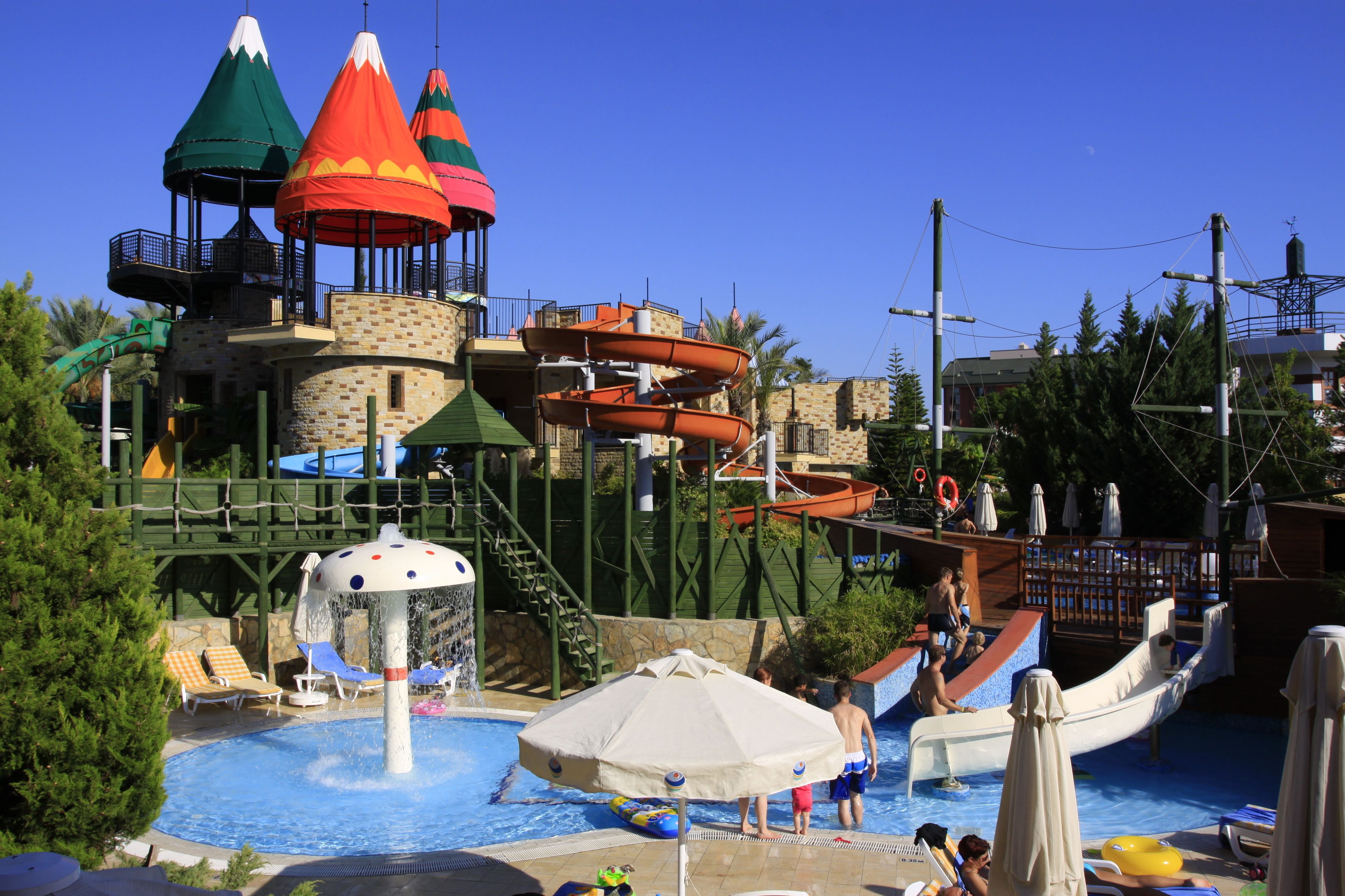 Een waterpark met een zwembad, glijbanen en kleurrijke parasols.