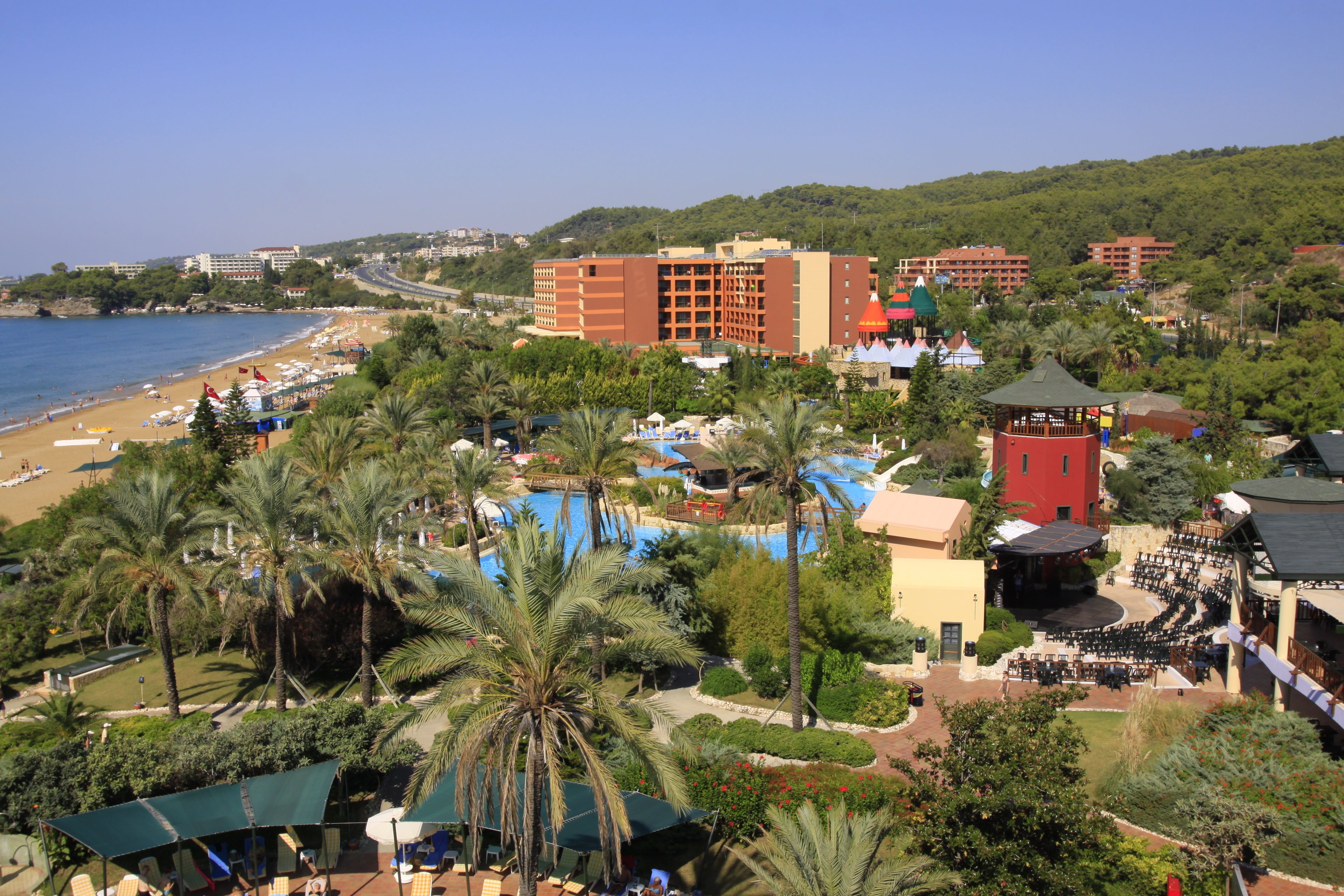 A resort with a pool area, palm trees, and a beach.