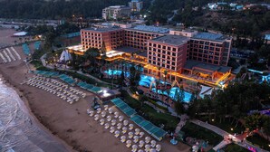 A hotel with multiple buildings, a beach with umbrellas, and a pool area. - AQI Pegasos Royal - All inclusive (Alanya)