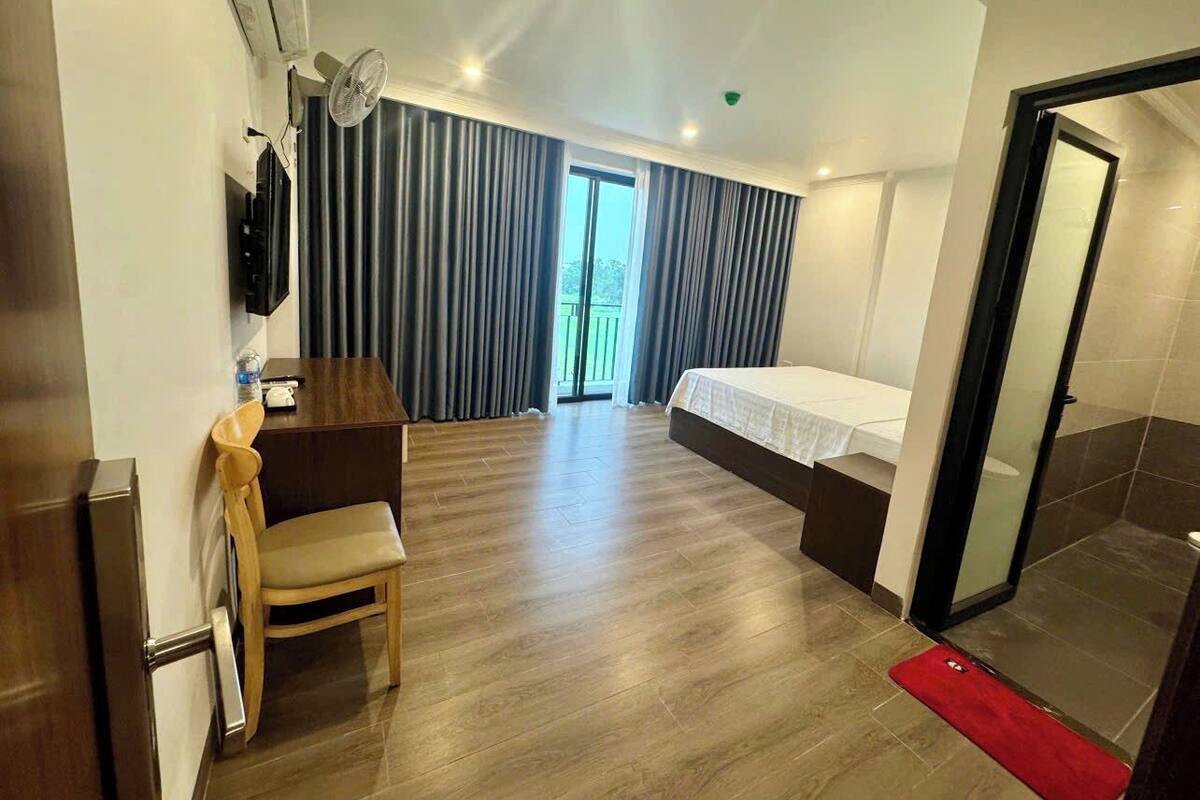 A hotel room with a bed, a desk, a chair, a TV, and a sliding door to the bathroom.