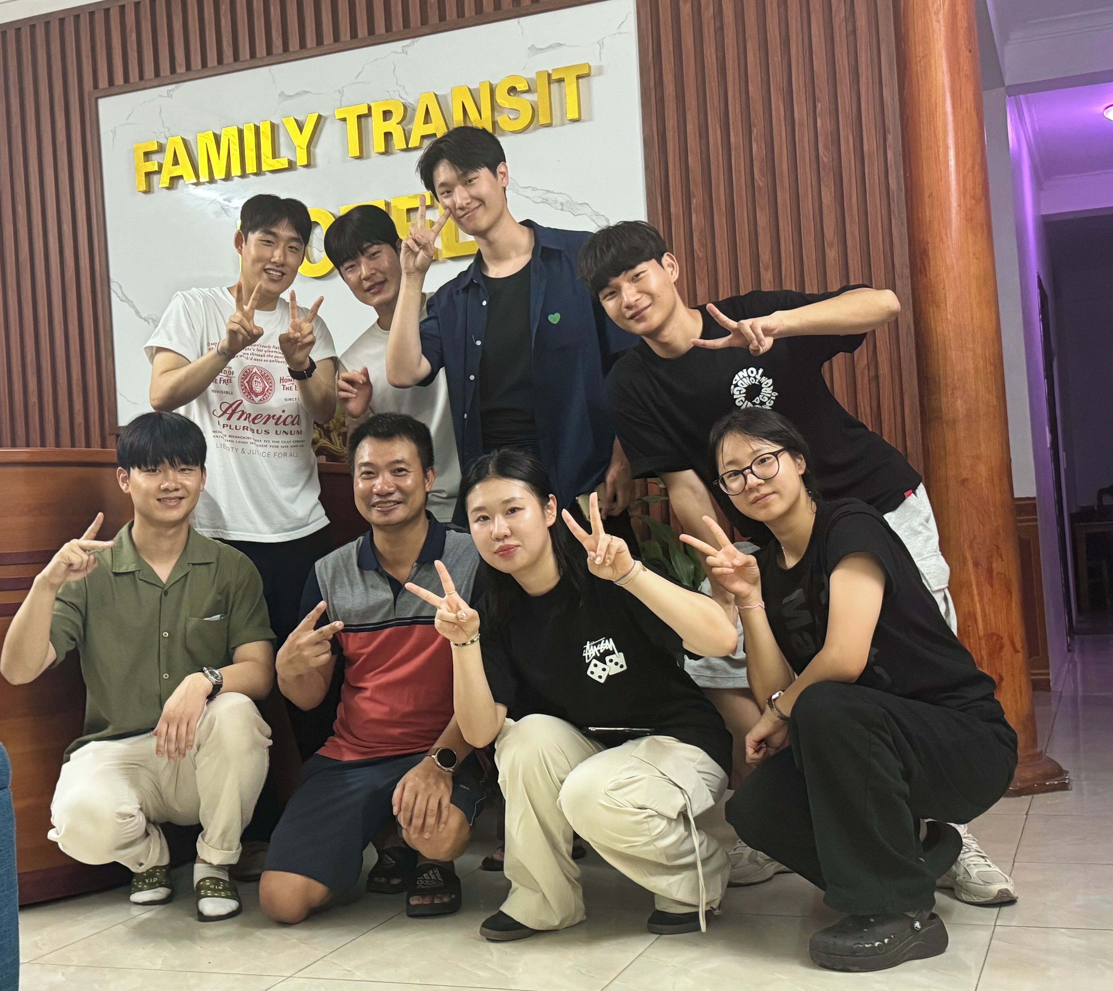 A group of people posing in front of a 'FAMILY TRANSIT' sign.