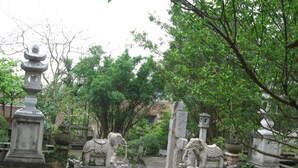 A courtyard with stone statues, including elephants and a pagoda, surrounded by trees. - Family Transit Hotel (Hanoi)