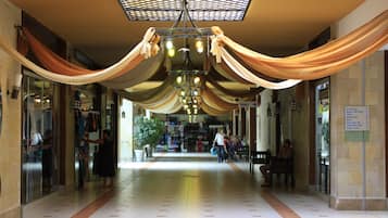 A corridor with draped fabric, a chandelier, and a sign indicating the location of toilets.