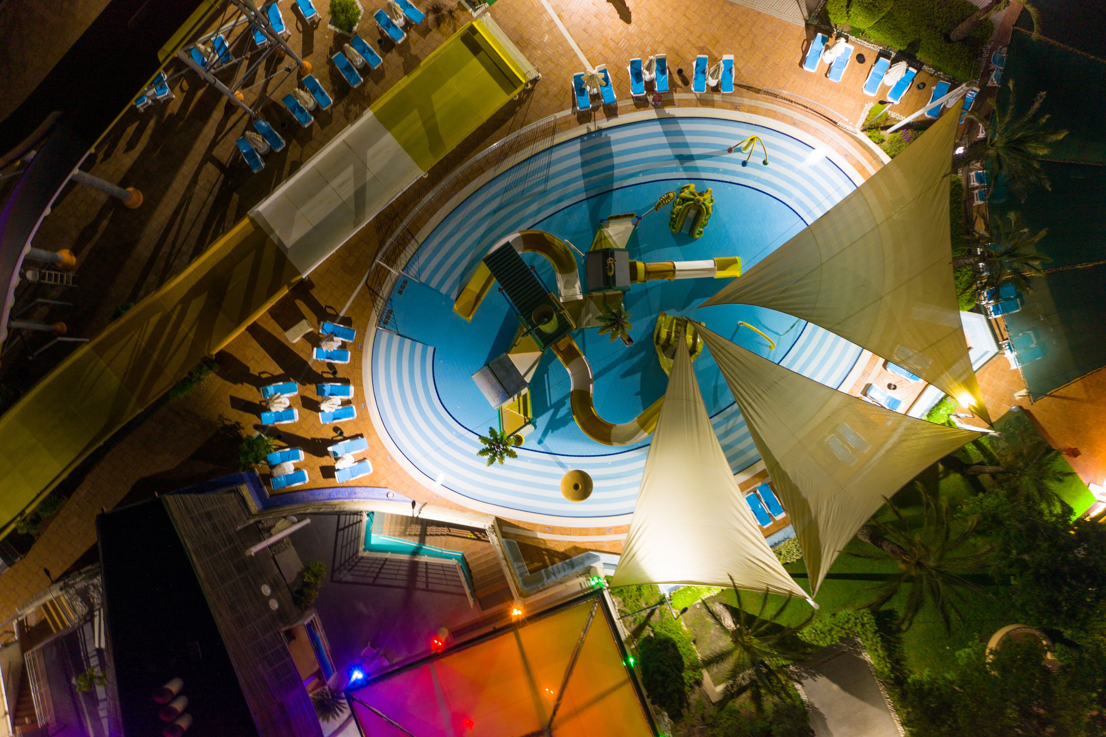 Una piscina circolare circondata da diverse poltrone prendisole e ombrelloni.