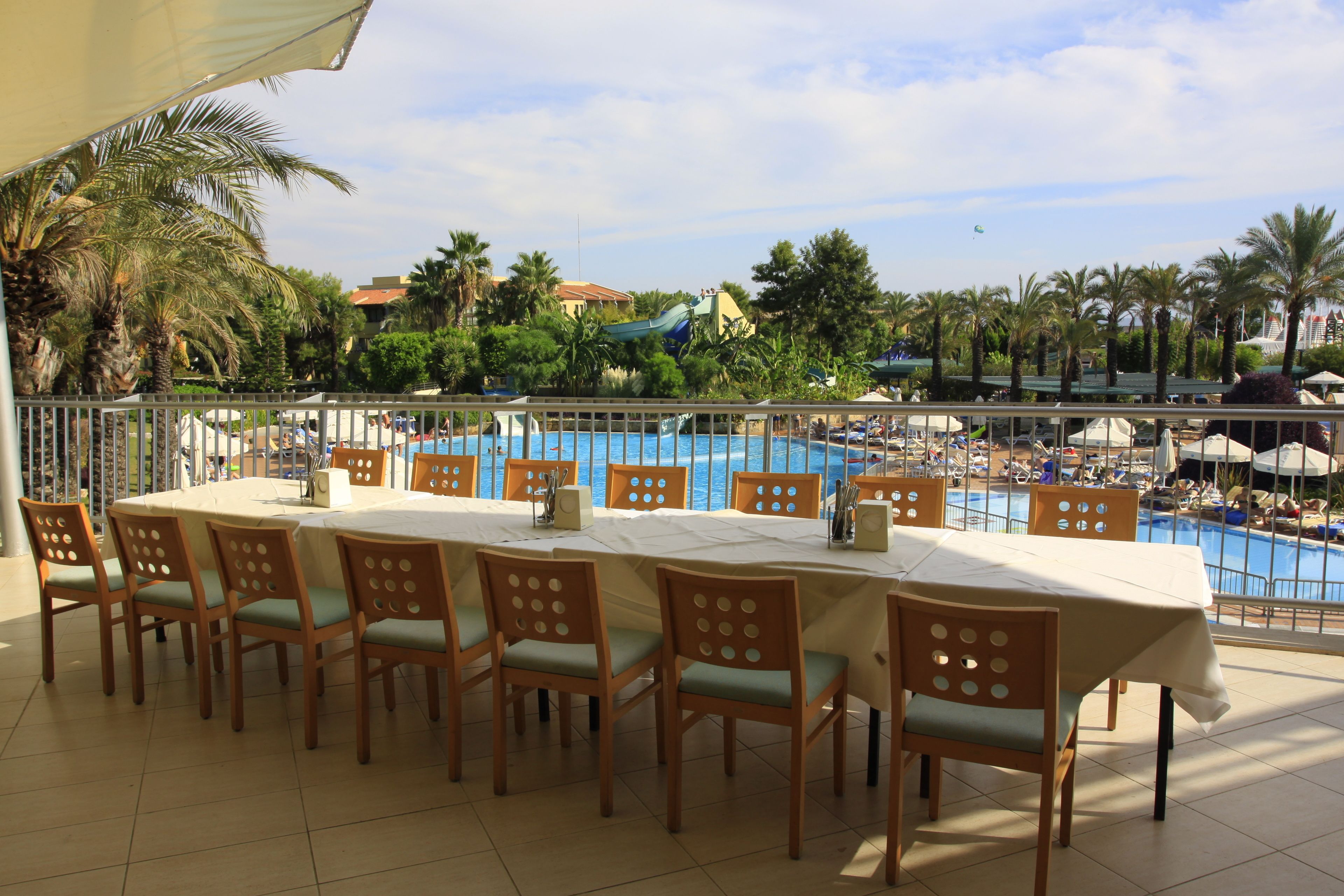 A dining area with a view of a pool and palm trees.