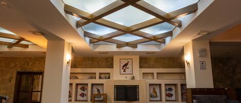 A spacious room with a high ceiling, skylight, fireplace, and artwork on the walls.