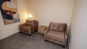 A room with two sofas, a small ottoman, and a wall-mounted lamp.