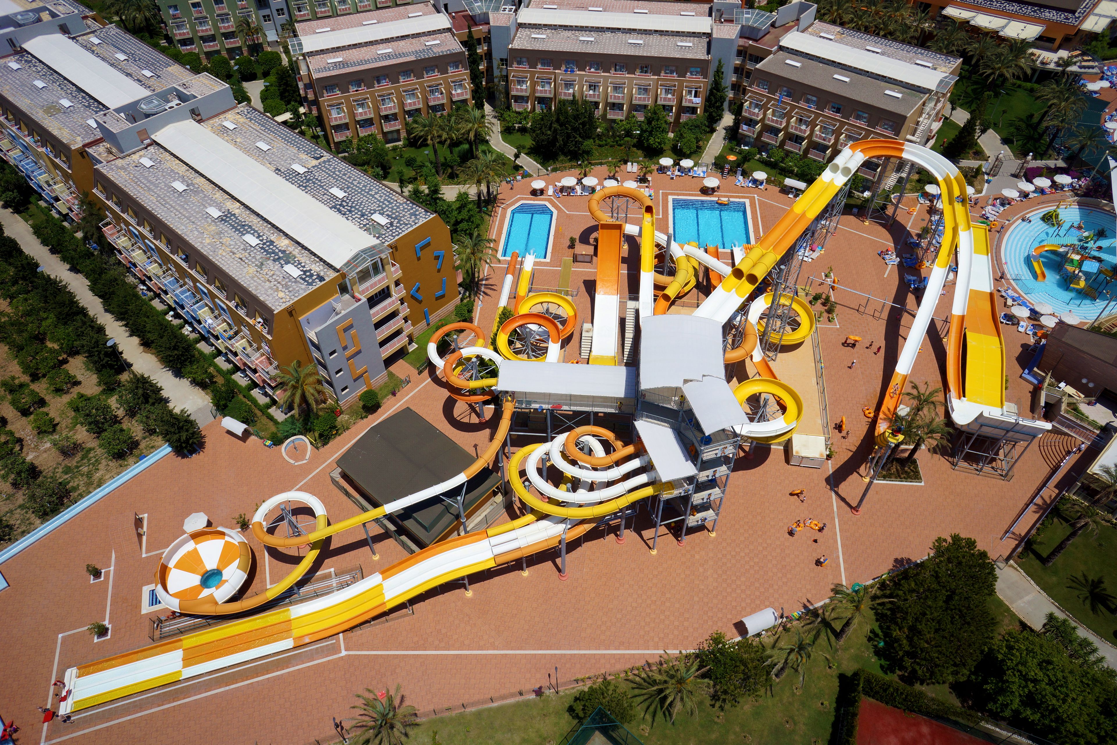 An aerial view of a hotel with multiple swimming pools, a water park, and a large parking area.