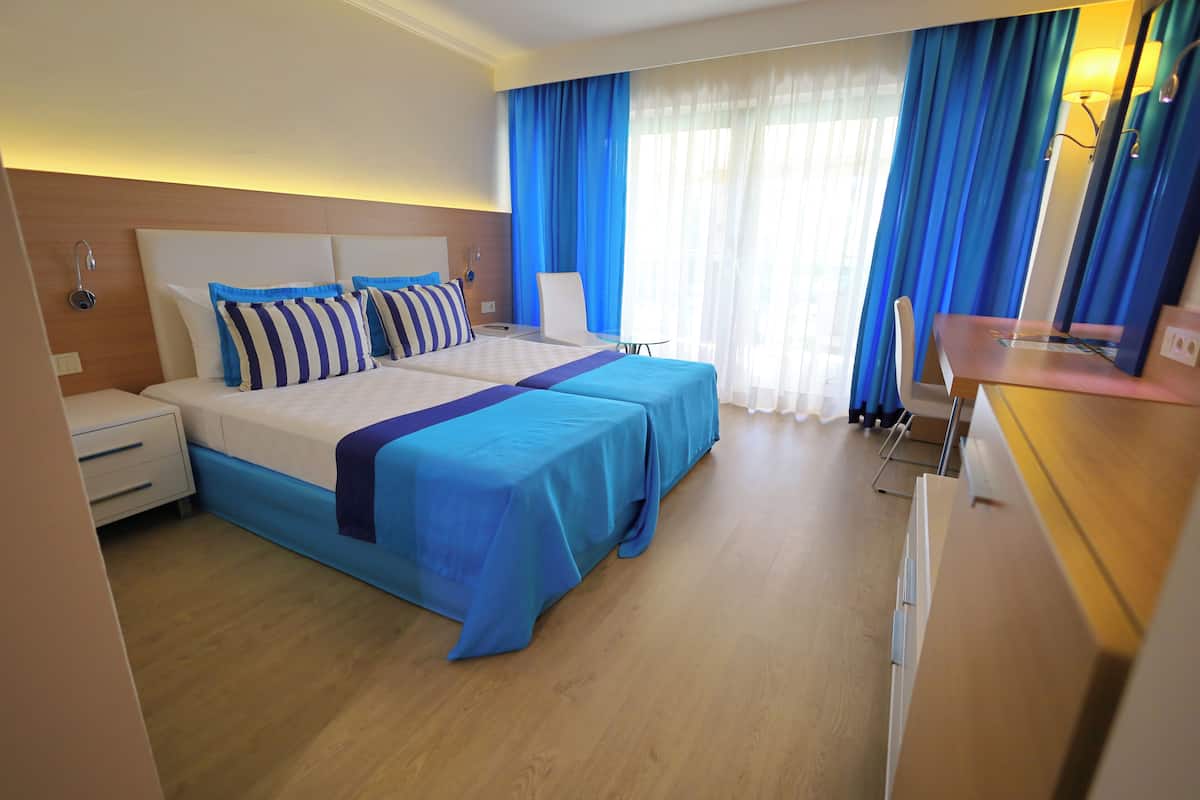 Una habitación de hotel con una cama, mesitas de noche, un escritorio y una silla.