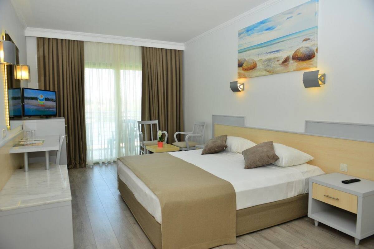 Una habitación de hotel con cama, mesita de noche, escritorio y silla.
