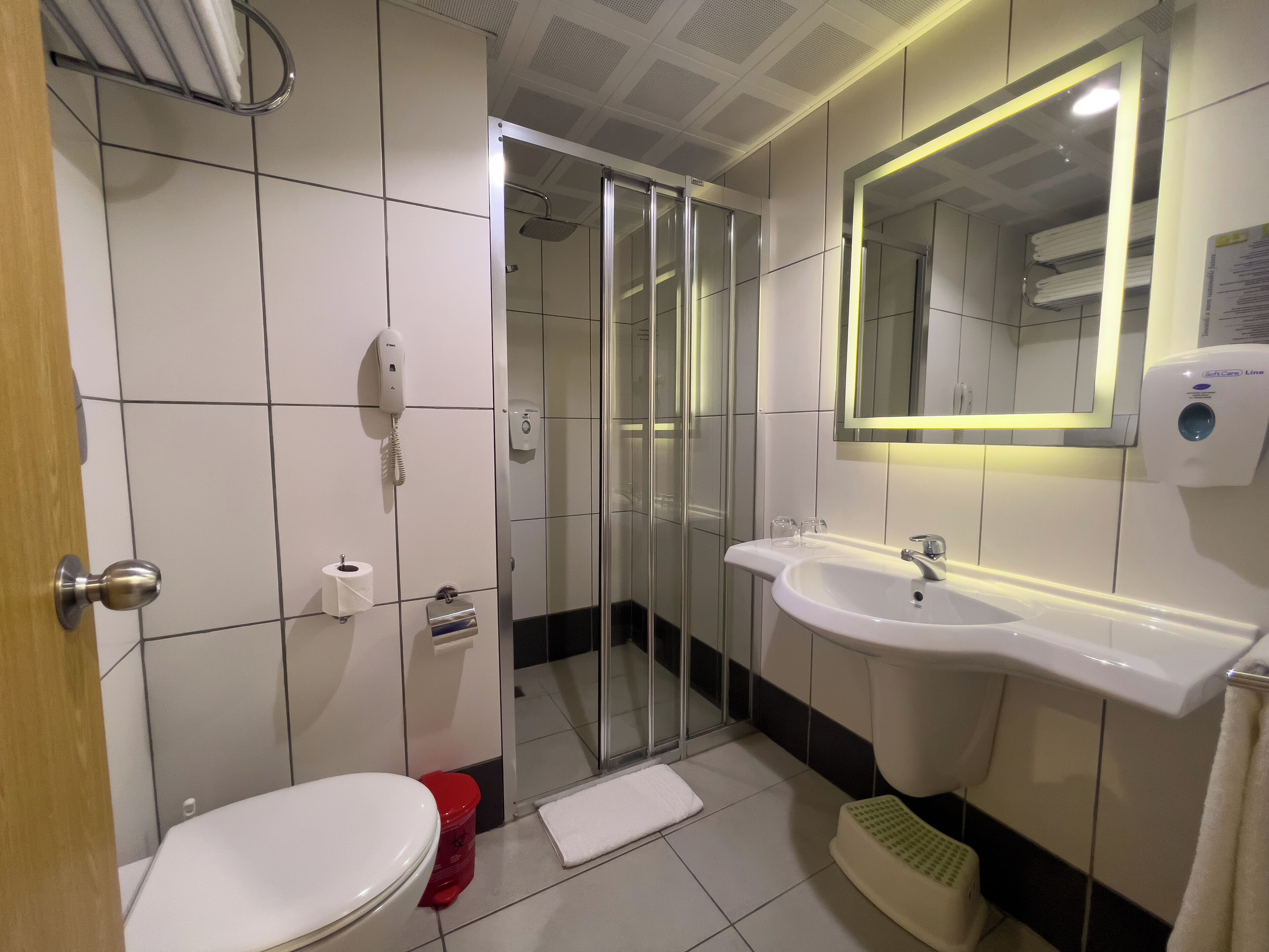 A modern bathroom with a toilet, a sink, a shower, and a mirror.