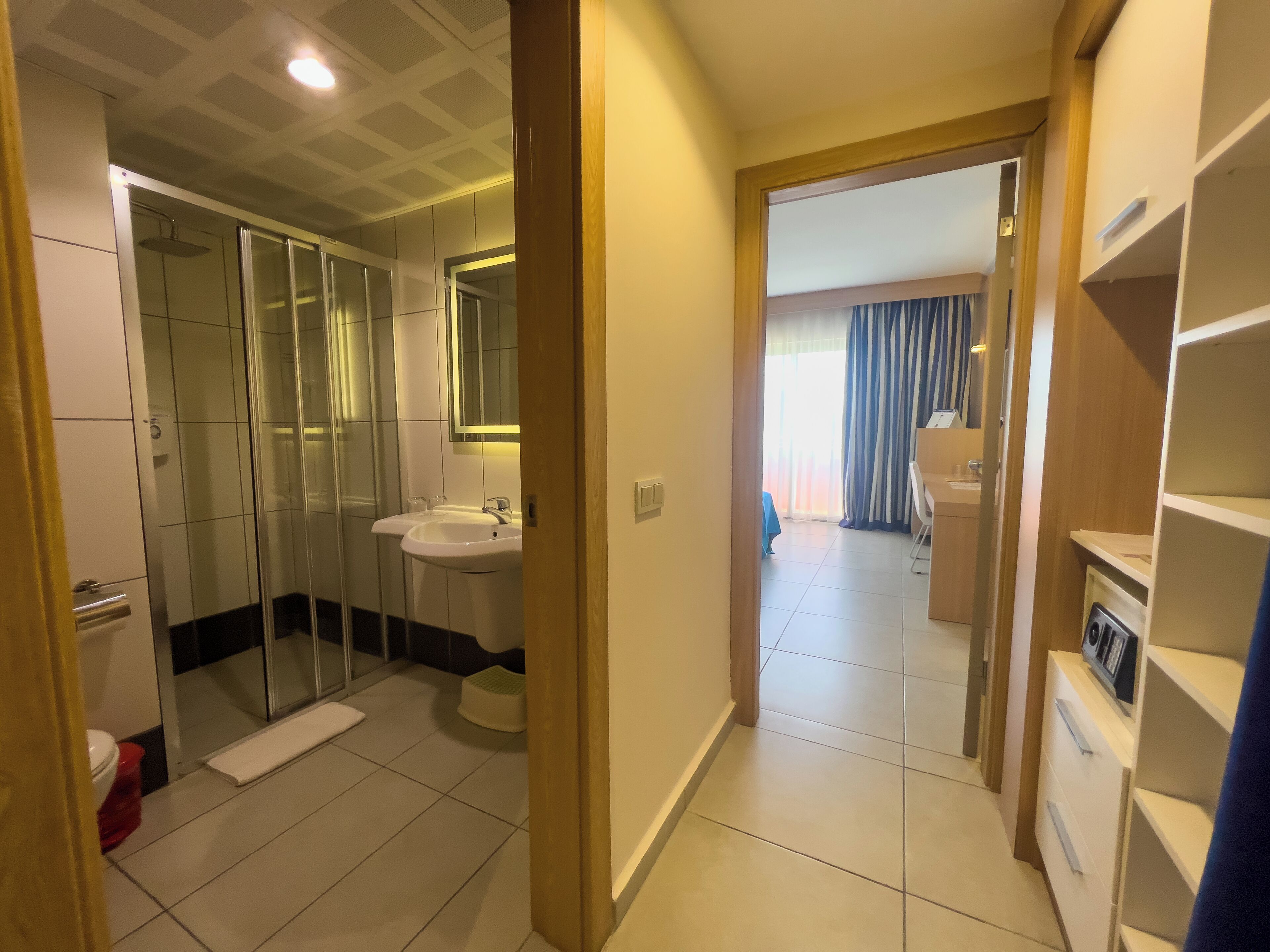 Une salle de bain d’hôtel avec une douche à parois de verre, un lavabo et un miroir.
