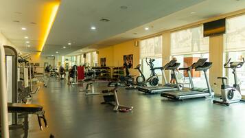 Un gimnasio con cintas de correr, bicicletas estáticas y máquinas de pesas.