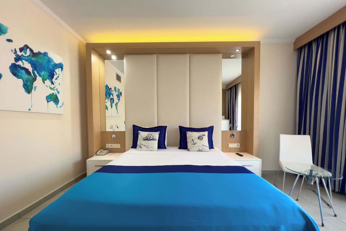 Una habitación de hotel moderna con una cama grande, dos almohadas, una mesita de noche, una silla y un cuadro con un mapa del mundo en la pared.